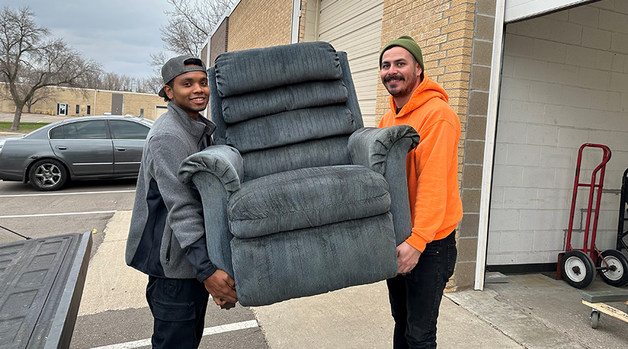Volunteers moving a couch into the non-profit Bridging